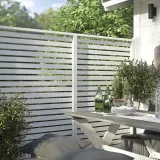 Modern vitt staket ger stilig staket inspiration. En uteplats med bord, stolar och grönska.