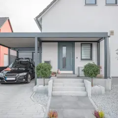 Modernt garage med tak som kan byggas om till bostad. En svart bil står parkerad under taket.
