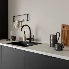 Svart kök med komposit bänkskiva. Nackdelar kan vara att den kan repas, men den här ser fin ut med svarta detaljer.