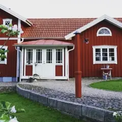 Rött hus med vita fönster och dörrar, en vacker trädgård med blommande träd. Planer på att bygga ut gammalt hus syns inte, men det ser ut som ett drömhem.