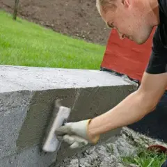 Man puts finishing touches on a gjuta betongplatta with a trowel.