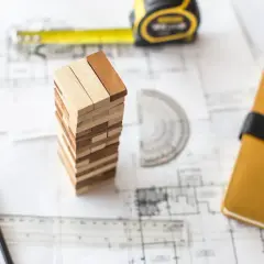 Ritningar, måttband, pennor och en Jenga-torn som symboliserar planeringen för att renovera garage.