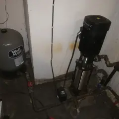 En hydropress med till och frånslagstryck, en trycktank och en pump i ett utrymme.