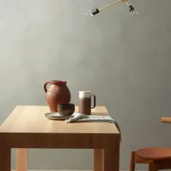 Enkel inredning med träbord, keramik och en stol. Väggen har en matt, kalkfärgad yta, där kalkfärg nackdelar kan vara att den är känslig för fläckar.