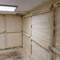 Hörnet i ett garage där väggarna är täckta med isolerande skum. En ljusramp lyser upp taket.
