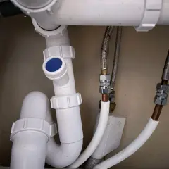 Detaljerad vy av avloppsrör med en blå topp, troligen en vakuumventil avlopp placering. Flexibla slangar ansluter till vattenledningar.