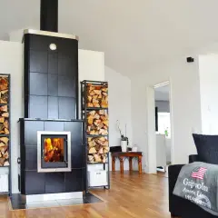 En modern kamin i uterummet med ved i staplar på sidorna. En mysig plats att värma sig vid.