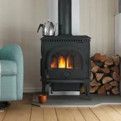 En mysig kamin med eld, ved och en tekanna. Tänk på installera kamin pris för en varm vinter.