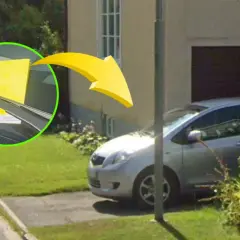 Gul parkeringsbot på vindrutan av en silverfärgad bil i ett villaområde. Kontrollera regler parkering villaområde.