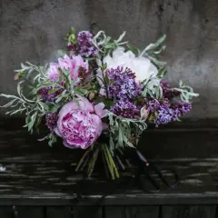 En bukett med rosa pioner, vita pioner och lila syren. Vackra snittblommor sorter som ser ut att vara nyss plockade.