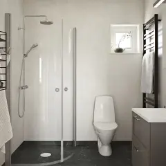 Modernt badrum med dusch, toalett och kommod. Mörk våtrumsmatta ger en lyxig känsla och inspiration för ditt eget badrum.