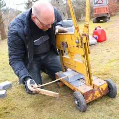 Man klipper marksten med en gul maskin.