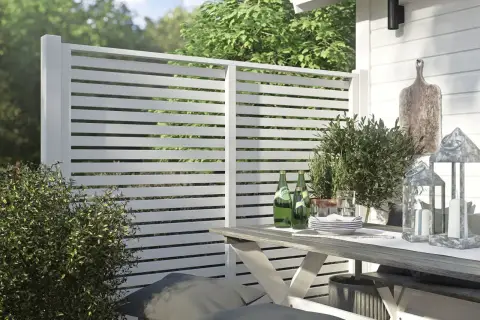 Modern vitt staket ger stilig staket inspiration. En uteplats med bord, stolar och grönska.
