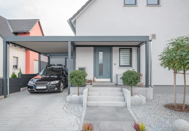 Modernt garage med tak som kan byggas om till bostad. En svart bil står parkerad under taket.