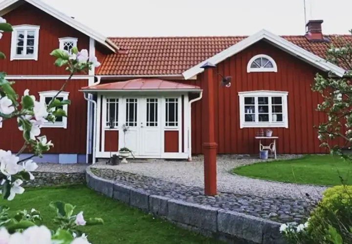 Rött hus med vita fönster och dörrar, en vacker trädgård med blommande träd. Planer på att bygga ut gammalt hus syns inte, men det ser ut som ett drömhem.
