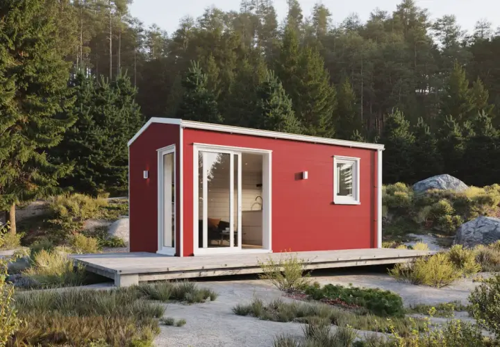 Röd friggebod med stora fönster och altan, placerad i en skogsglänta. Perfekt för dig som vill flytta friggebod och skapa en egen oas.