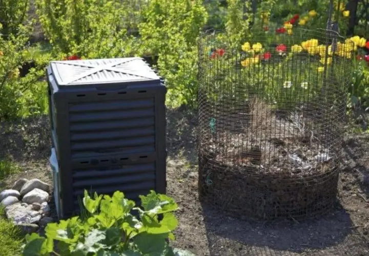 En svart kompostbehållare och en rund kompost av nät står i en trädgård. En bra plats att börja bygga varmkompost.