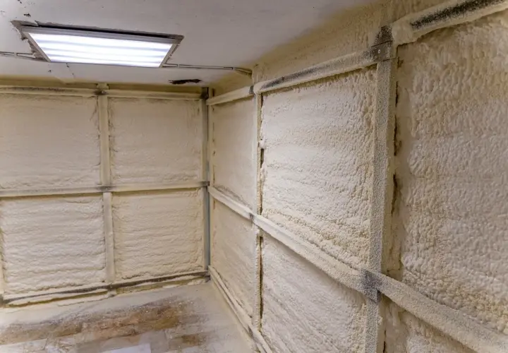 Hörnet i ett garage där väggarna är täckta med isolerande skum. En ljusramp lyser upp taket.
