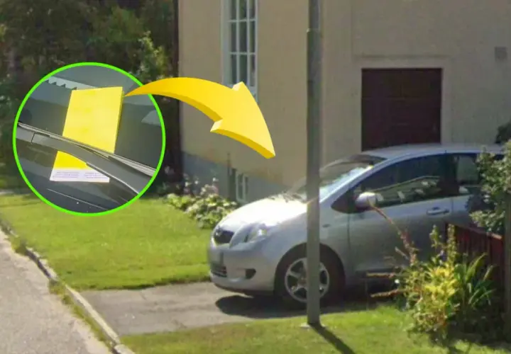 Gul parkeringsbot på vindrutan av en silverfärgad bil i ett villaområde. Kontrollera regler parkering villaområde.