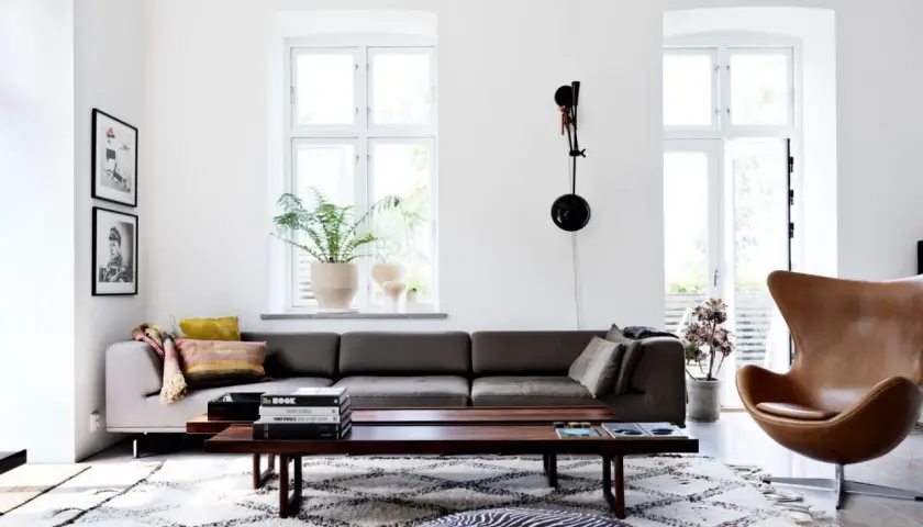 Vardagsrum med mörkgrå soffa, brun läderfåtölj och ett lågt träbord. Väggarna är målade i NCS S 0502-Y Stockholmsvit.