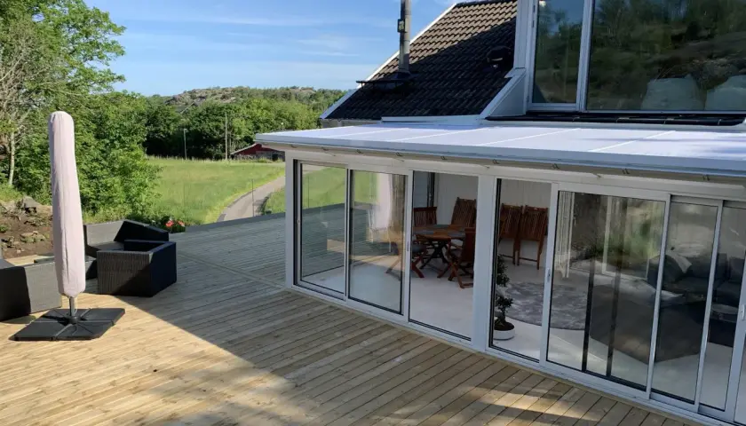 Ny slipad altan med glasveranda och utemöbler. Perfekt för att njuta av sommaren.