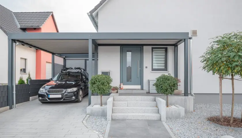 Modernt garage med tak som kan byggas om till bostad. En svart bil står parkerad under taket.