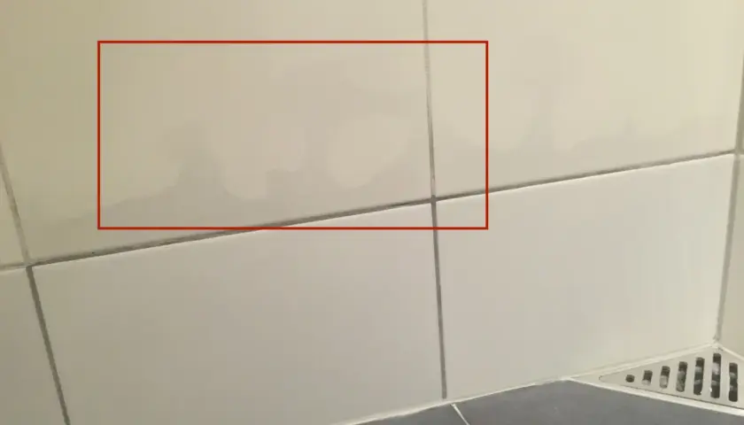 Fuktskada kakel syns som mörka fläckar på ljusa väggplattor. Vatten har trängt in.