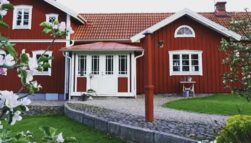 Rött hus med vita fönster och dörrar, en vacker trädgård med blommande träd. Planer på att bygga ut gammalt hus syns inte, men det ser ut som ett drömhem.