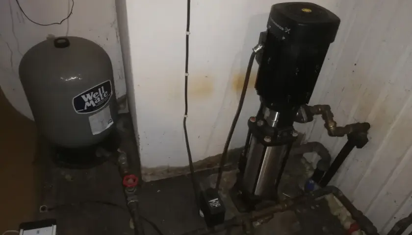 En hydropress med till och frånslagstryck, en trycktank och en pump i ett utrymme.