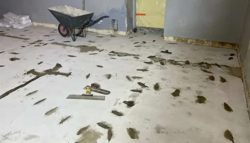 Arbetsplats för att laga betonggolv. Skottkärra, säckar med material och verktyg ligger redo.