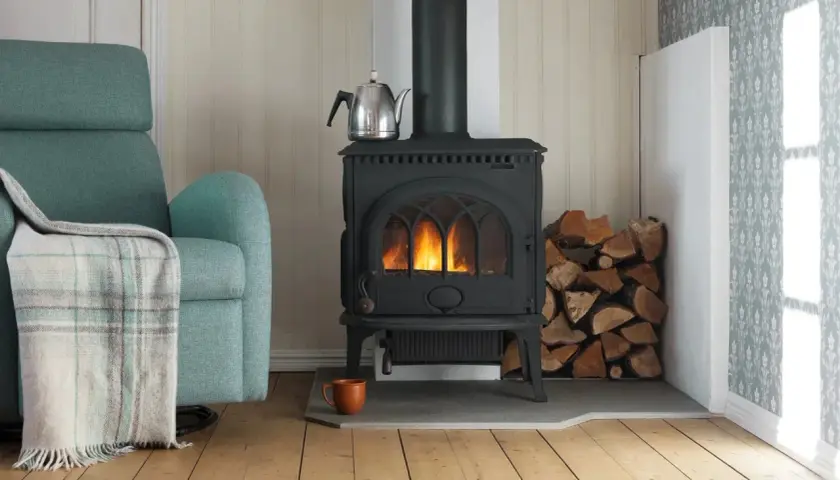 En mysig kamin med eld, ved och en tekanna. Tänk på installera kamin pris för en varm vinter.
