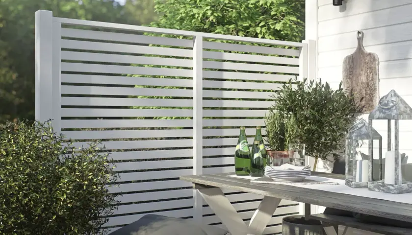 Modern vitt staket ger stilig staket inspiration. En uteplats med bord, stolar och grönska.