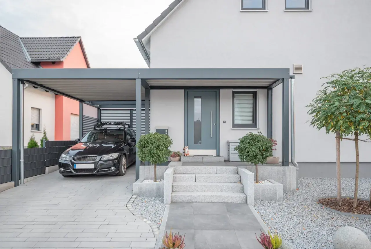 Modernt garage med tak som kan byggas om till bostad. En svart bil står parkerad under taket.