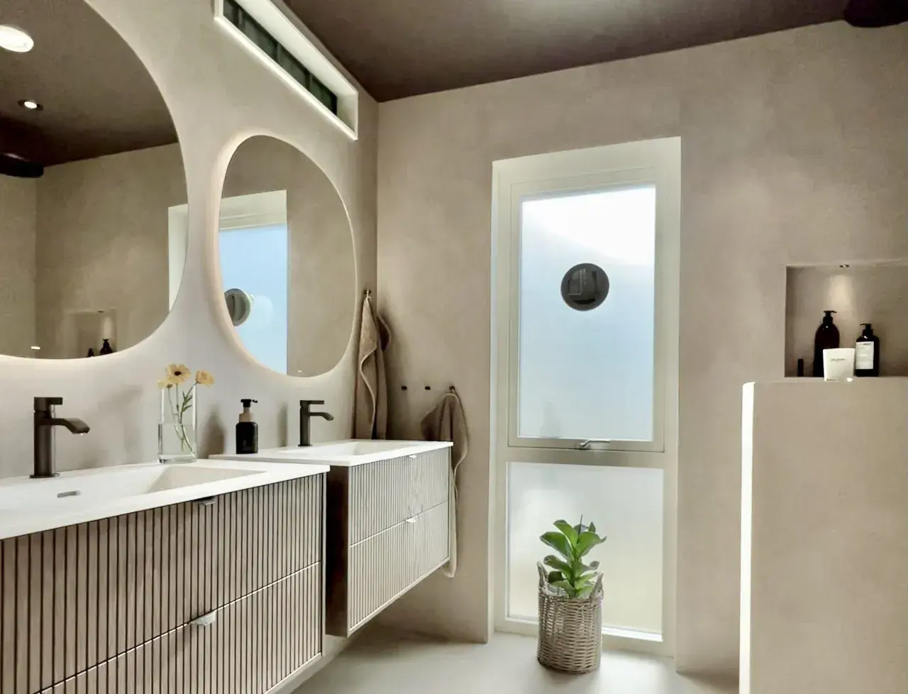 Modernt badrum med dubbla handfat och speglar. Väggarna har en slät, betongliknande finish, liknande microcement på kakel, vilket ger en lyxig och enhetlig känsla.