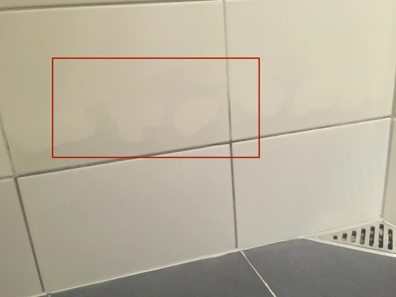 Fuktskada kakel syns som mörka fläckar på ljusa väggplattor. Vatten har trängt in.