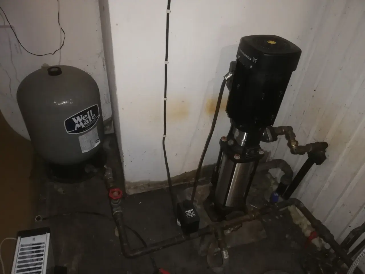 En hydropress med till och frånslagstryck, en trycktank och en pump i ett utrymme.