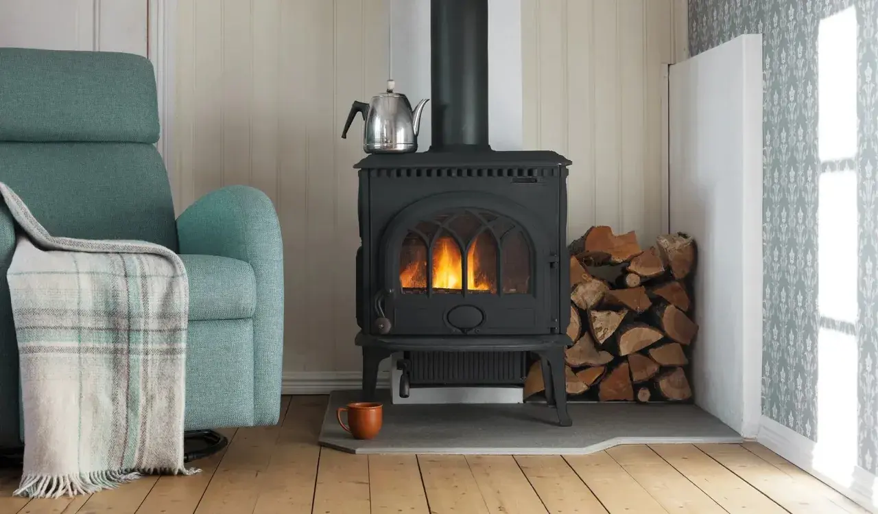En mysig kamin med eld, ved och en tekanna. Tänk på installera kamin pris för en varm vinter.