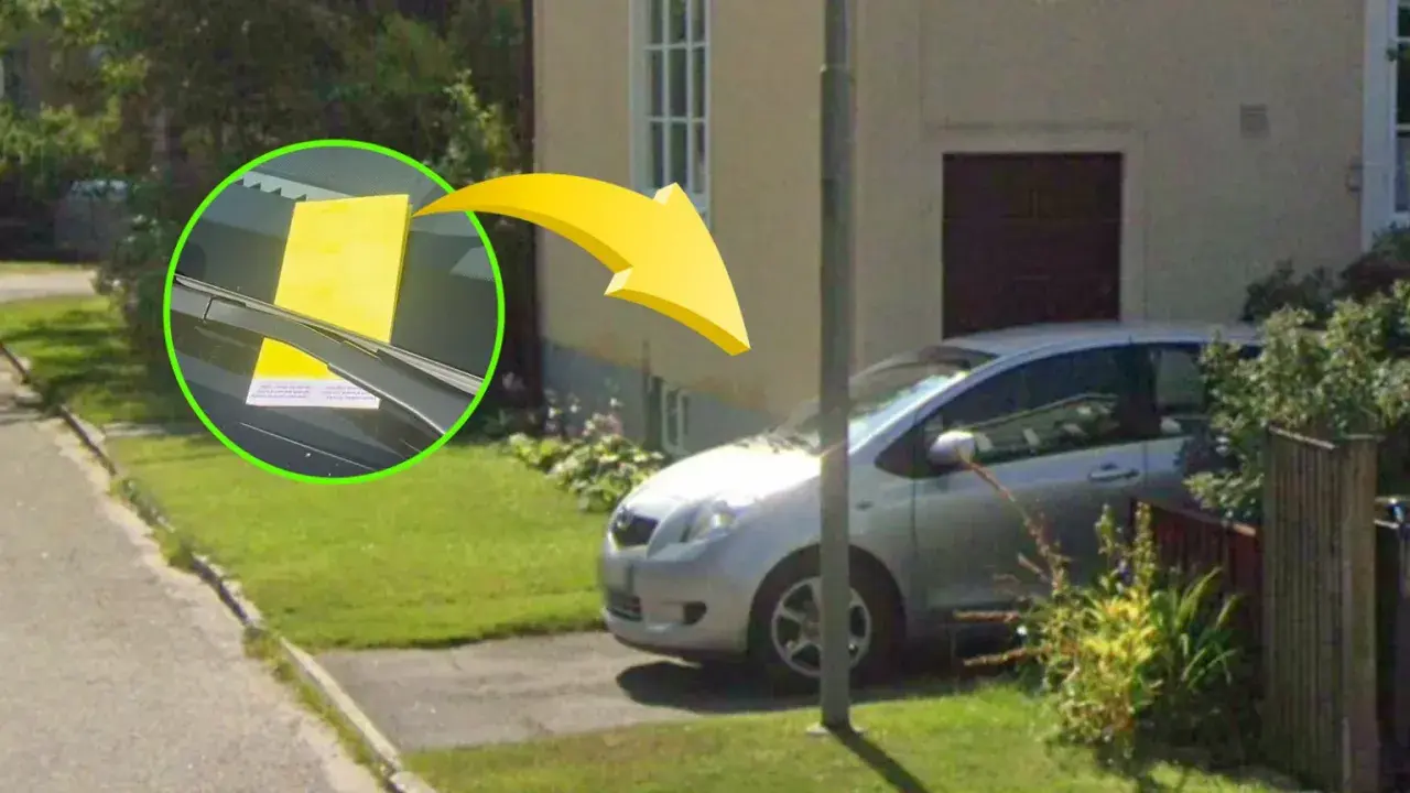 Gul parkeringsbot på vindrutan av en silverfärgad bil i ett villaområde. Kontrollera regler parkering villaområde.
