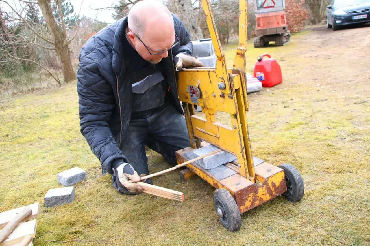 Man klipper marksten med en gul maskin.