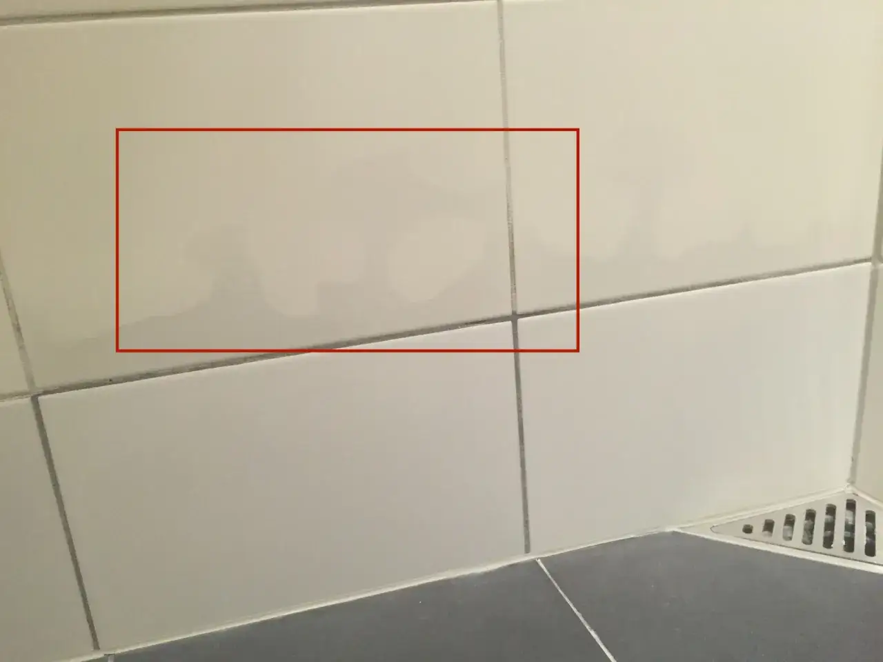 Fuktskada kakel syns som m&ouml;rka fl&auml;ckar p&aring; ljusa v&auml;ggplattor. Vatten har tr&auml;ngt in.