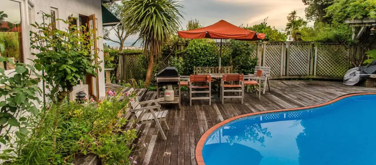 Trädäck med pool, matgrupp och grill. En härlig plats för sommaren, men funderar du på bygga pool kostnad?