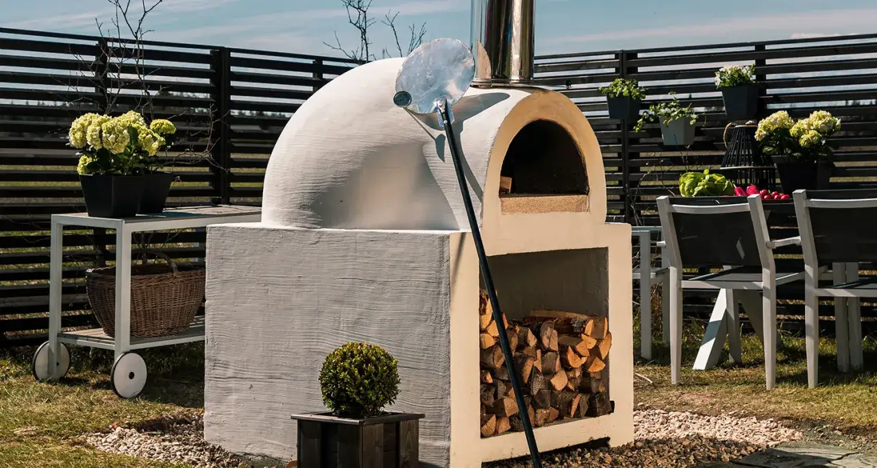 En vacker, nybyggd pizzaugn i trädgården, redo för att bygga den perfekta pizzan. Ved finns i förvaringen under.