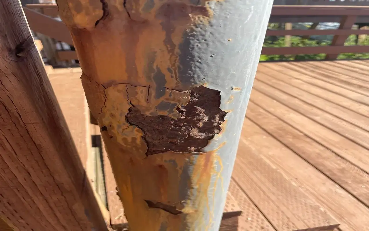 En metallstolpe med kraftig rost som flagnar. Det är dags att ta bort rost och skydda stolpen.