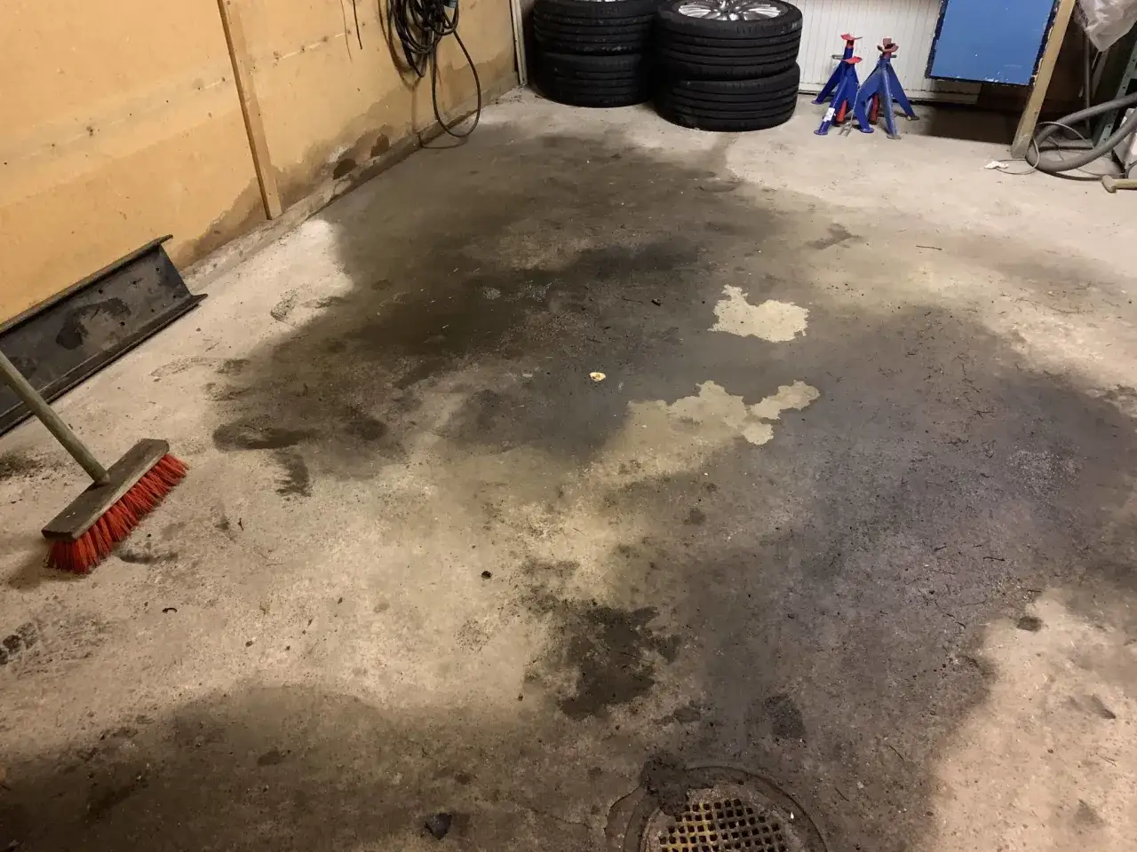 Mörk fukt i garage, med en röd borste redo att ta itu med problemet.
