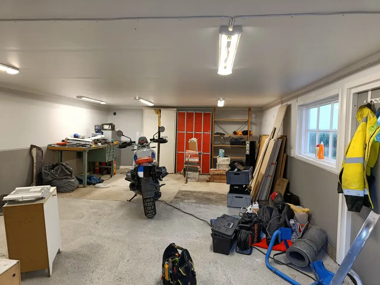 Motorcykel i ett garage som är redo för renovering. Verktyg och material ligger utspritt, redo för att fixa till det.