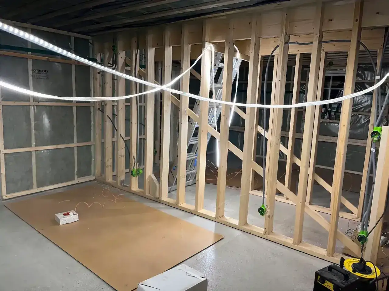 Byggarbetsplats d&auml;r man f&ouml;rbereder f&ouml;r att isolera tak inifr&aring;n. Tr&auml;reglar, isolering och elinstallationer syns.