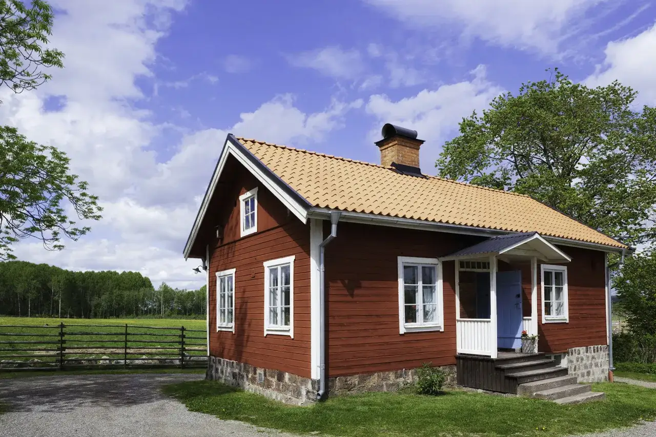 R&ouml;tt tr&auml;hus med tegeltak, redo att bygga ut. En vacker sommardag i Sverige.