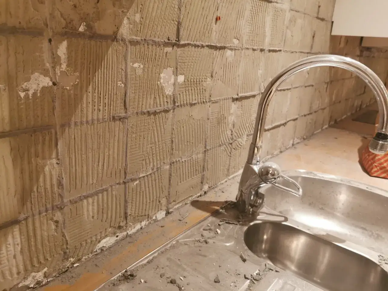 Renovering pågår: kakel tas bort med multiverktyg från väggen bakom diskbänken.