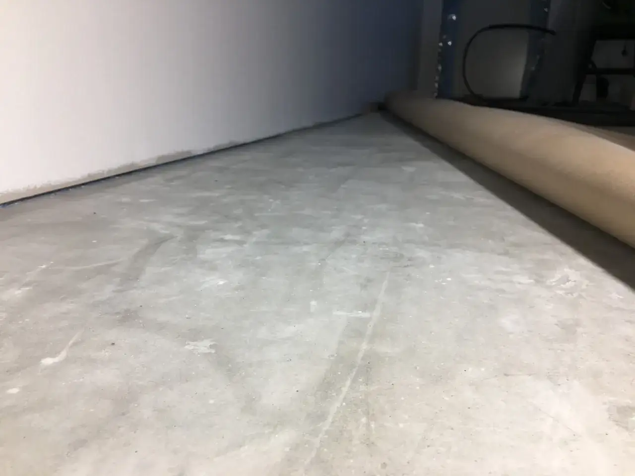 Oslipat betonggolv med en rulle skyddspapper. Undrar du över slipa betonggolv pris?