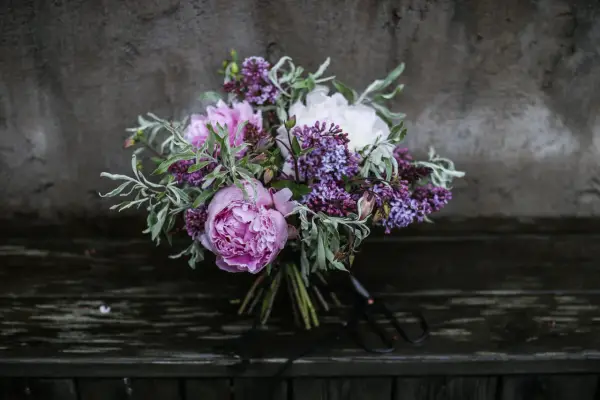 En bukett med rosa pioner, vita pioner och lila syren. Vackra snittblommor sorter som ser ut att vara nyss plockade.